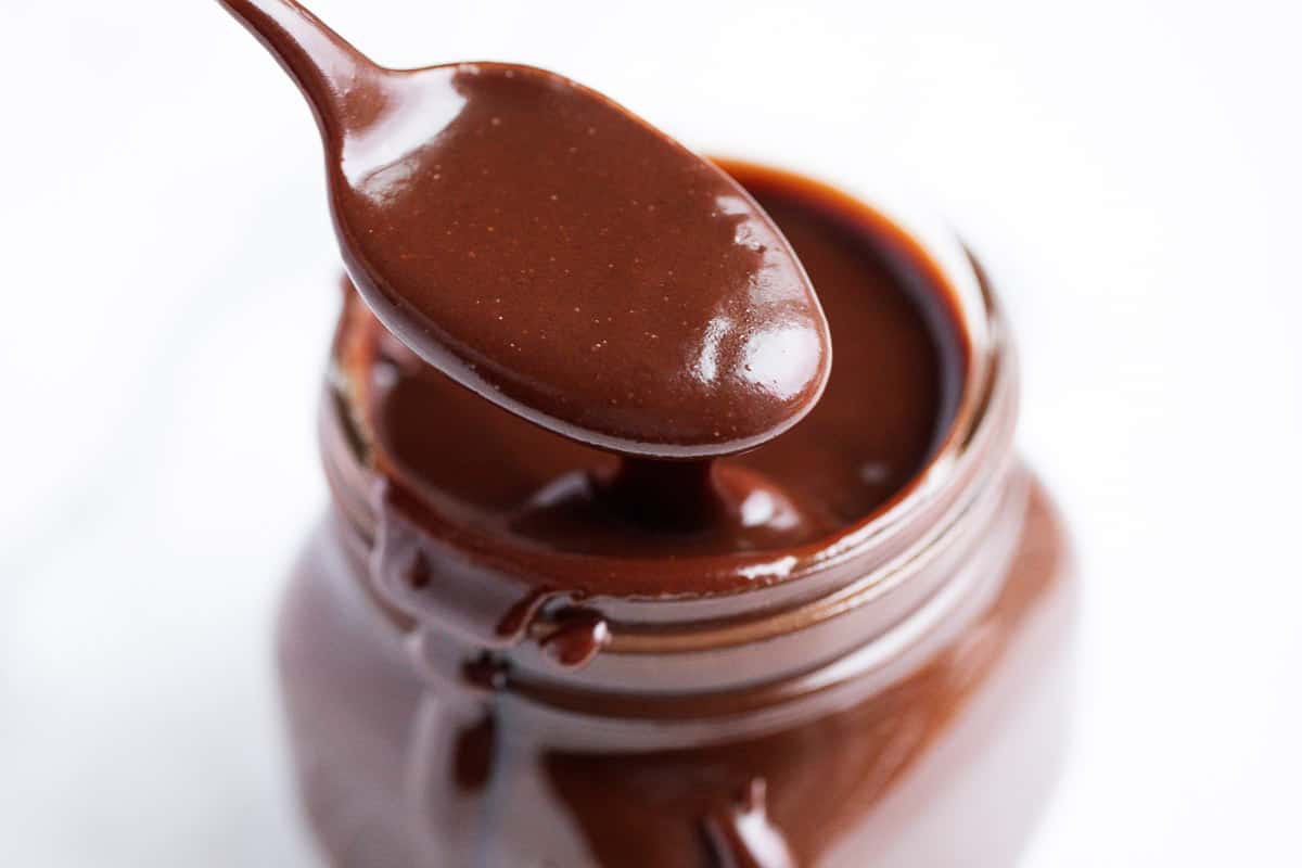 Hot fudge in a glass jar with spoon. 