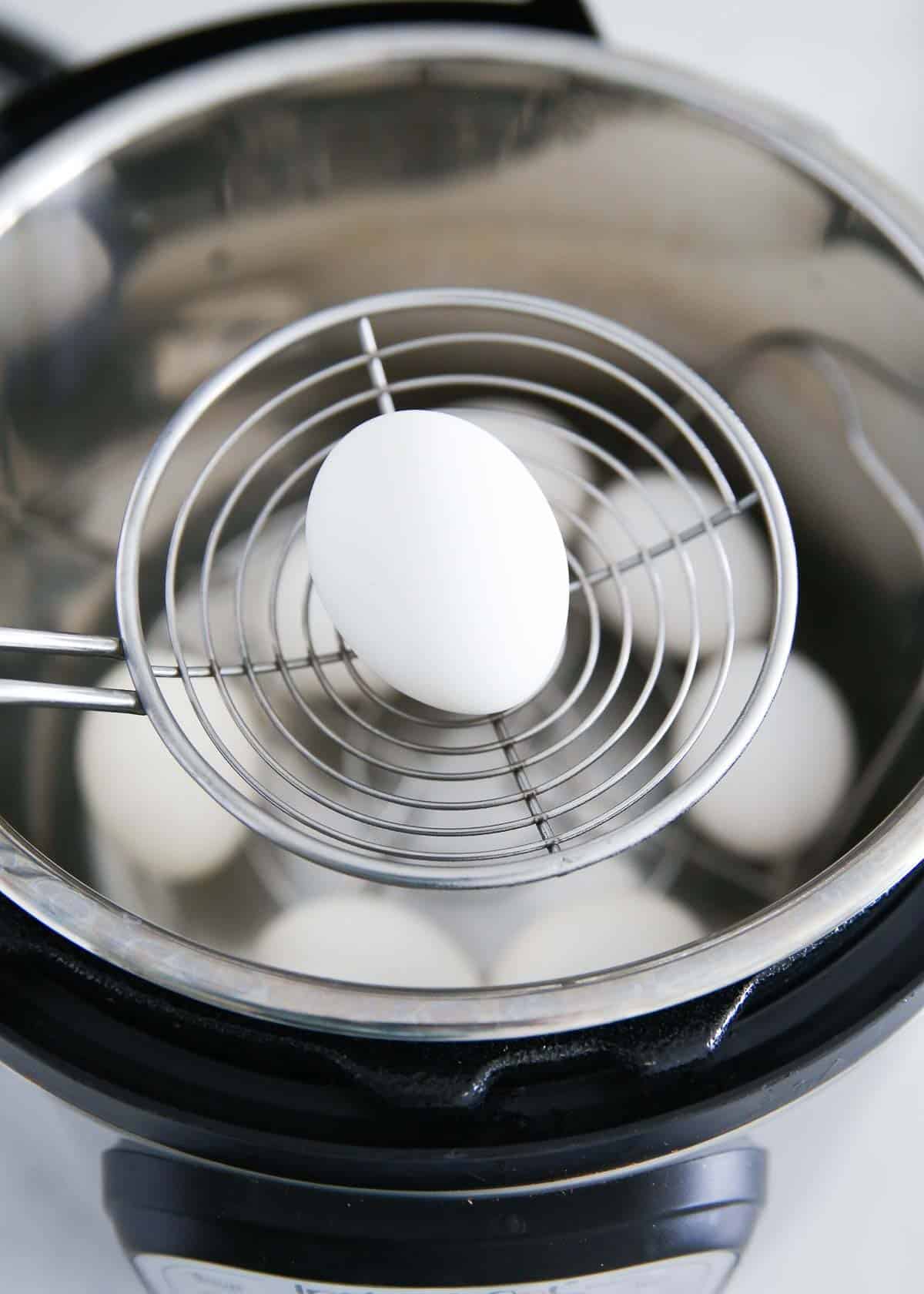 Removing egg from instant pot with a spoon.