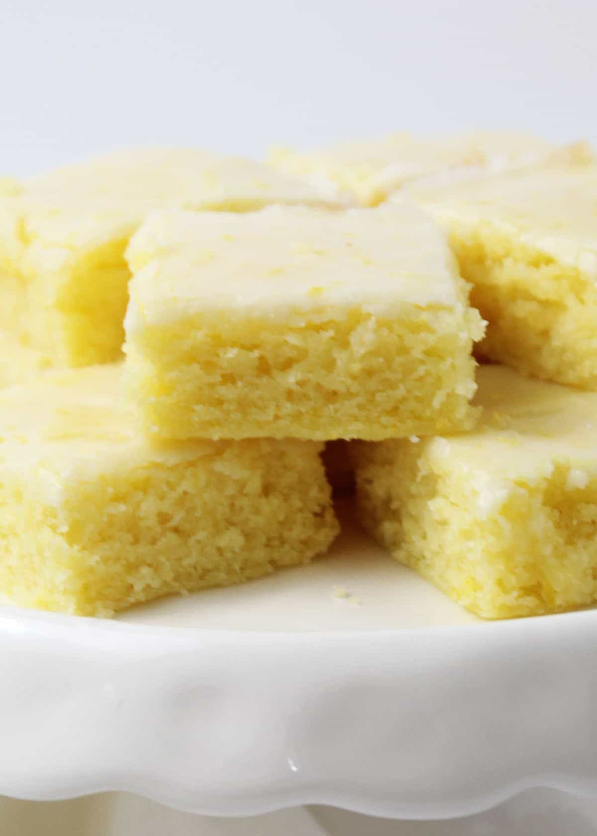 Lemon brownies stacked together on a white plate. 