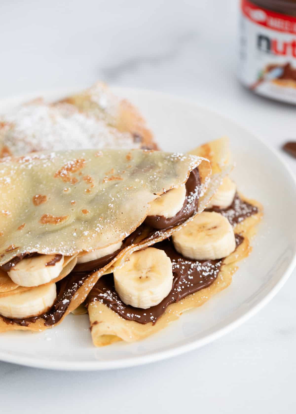 Nutella crepes folded in a triangle on a white plate. 