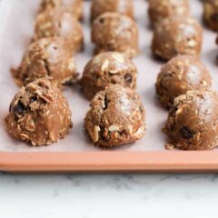 Chocolate peanut butter protein balls on a parchment paper lined baking sheet.