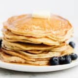 Stack of ricotta pancakes on white plate.