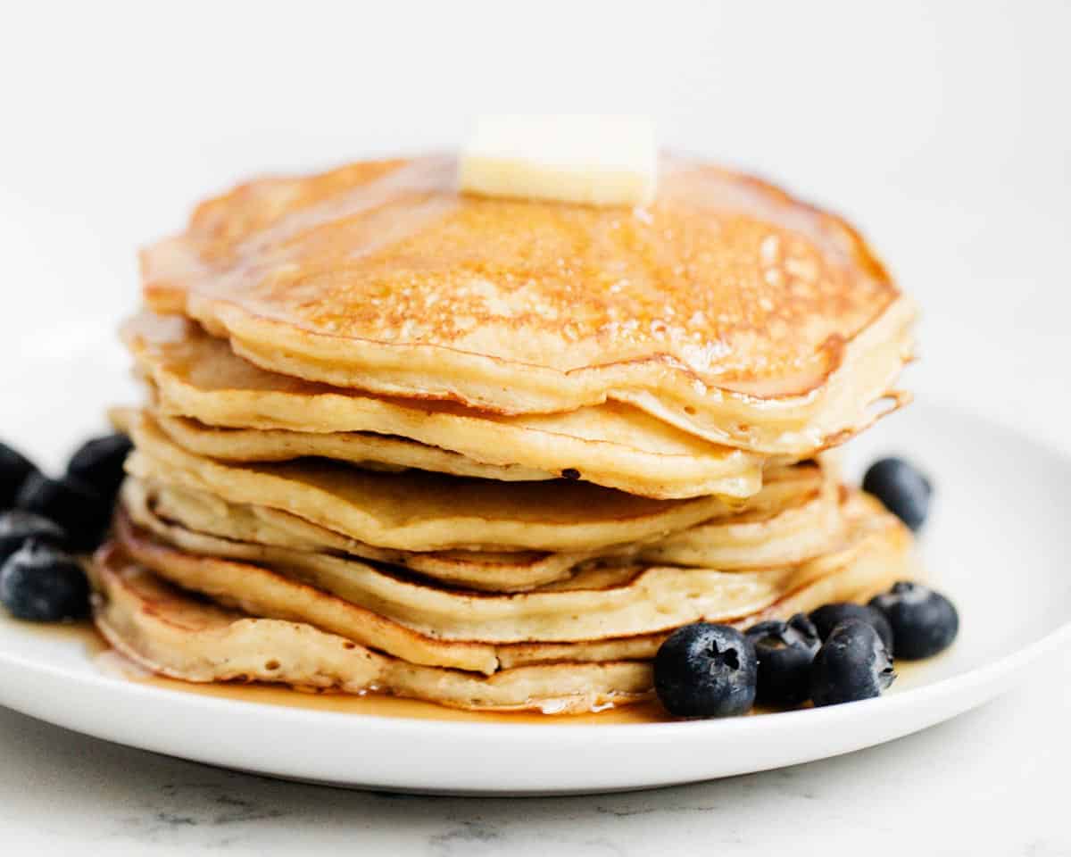 Stack of ricotta pancakes on white plate.