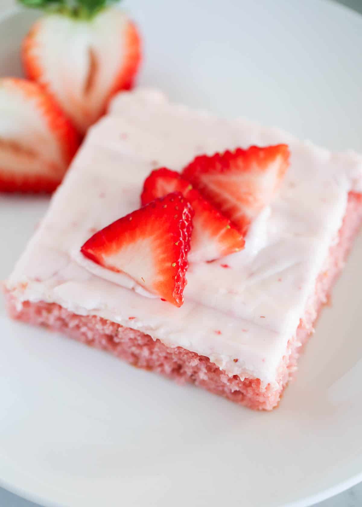 Strawberry brownies on a white plate with strawberry slices on top. 