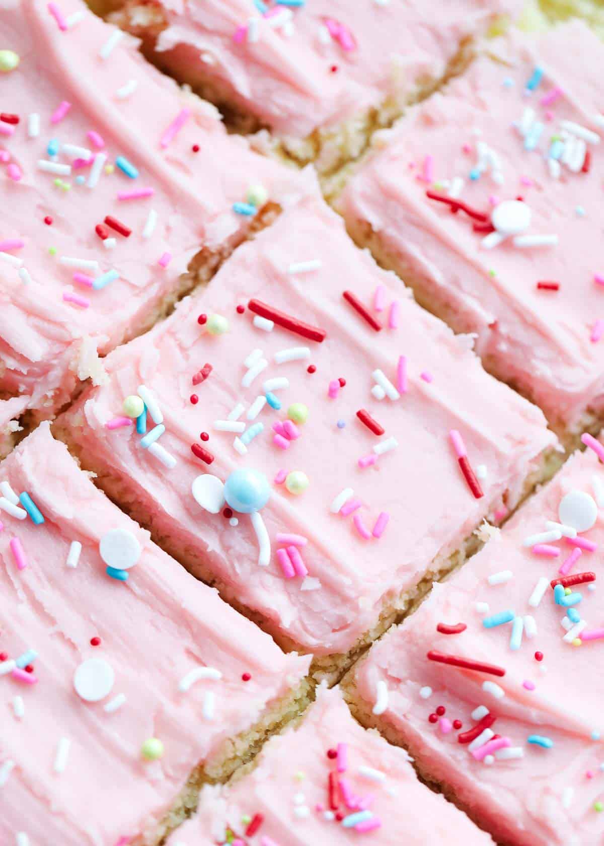 Sugar cookie bars with frosting and sprinkles cut into squares. 