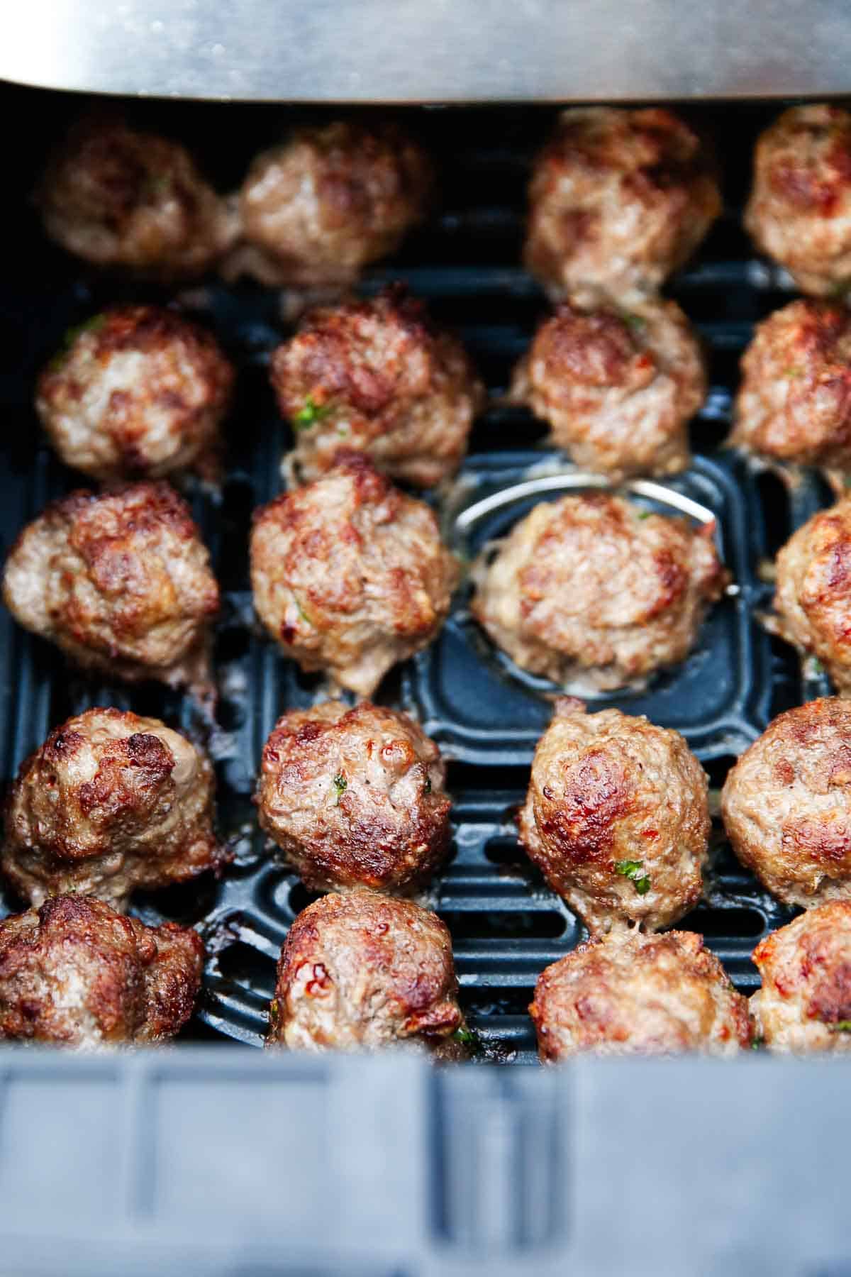 Tender and juicy air fryer meatballs are easy to make in just minutes. Enjoy a batch of these delicious homemade meatballs for a weeknight meal with pasta, in a sub or as an appetizer! Air fryer meatballs in air fryer basket.