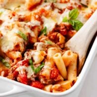 Spoonful of baked ziti in baking dish.