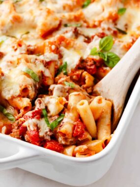 Spoonful of baked ziti in baking dish.