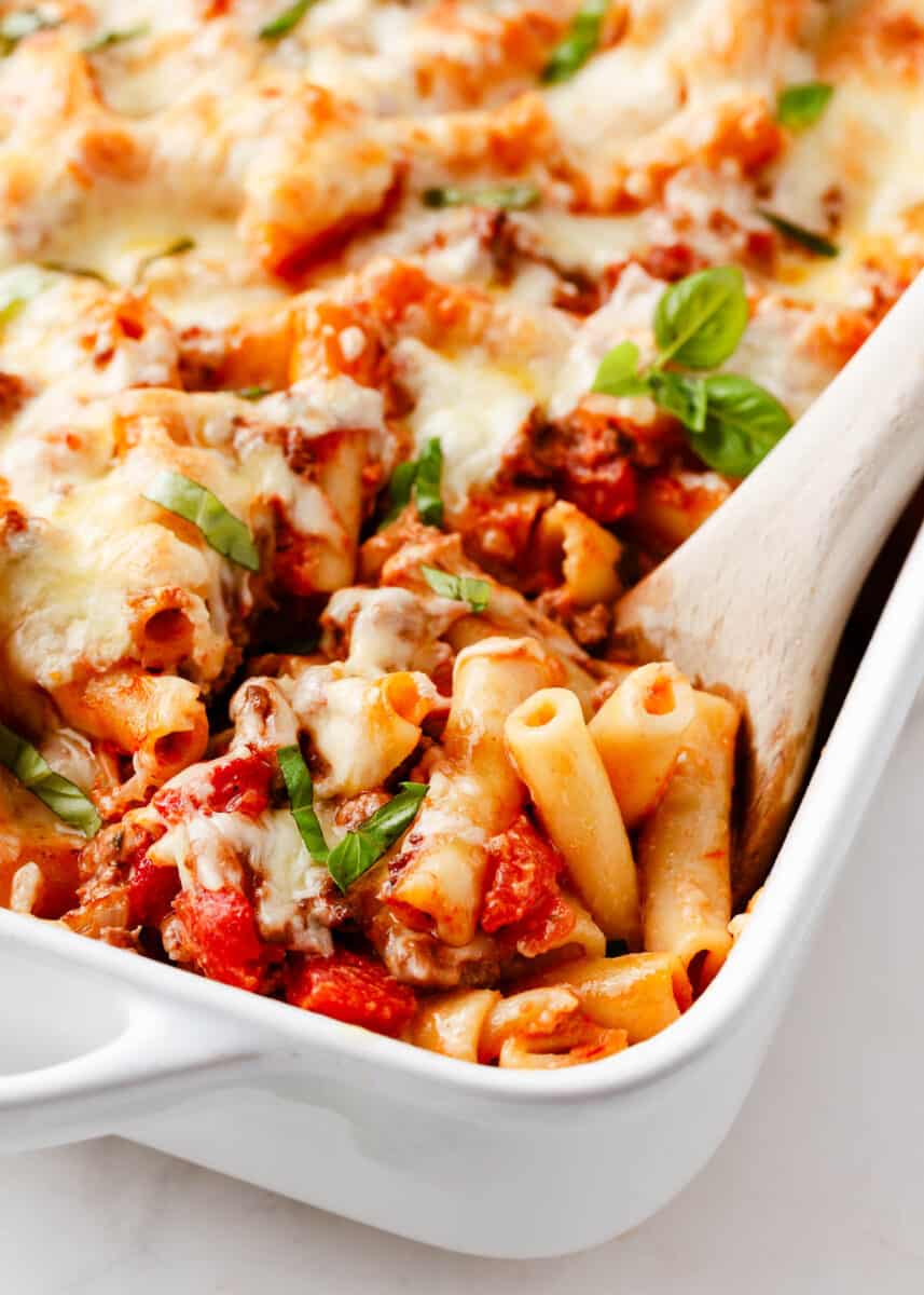 Spoonful of baked ziti in baking dish.