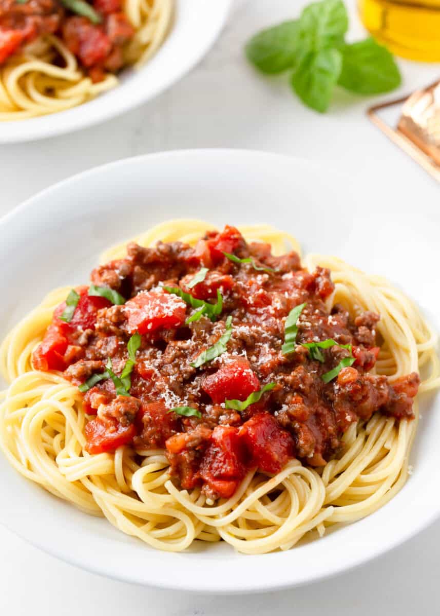 This easy spaghetti recipe with meat sauce is a family favorite! It adds a little flavor to the good ol' classic and is always a hit with the kids! Spaghetti in a white bowl.