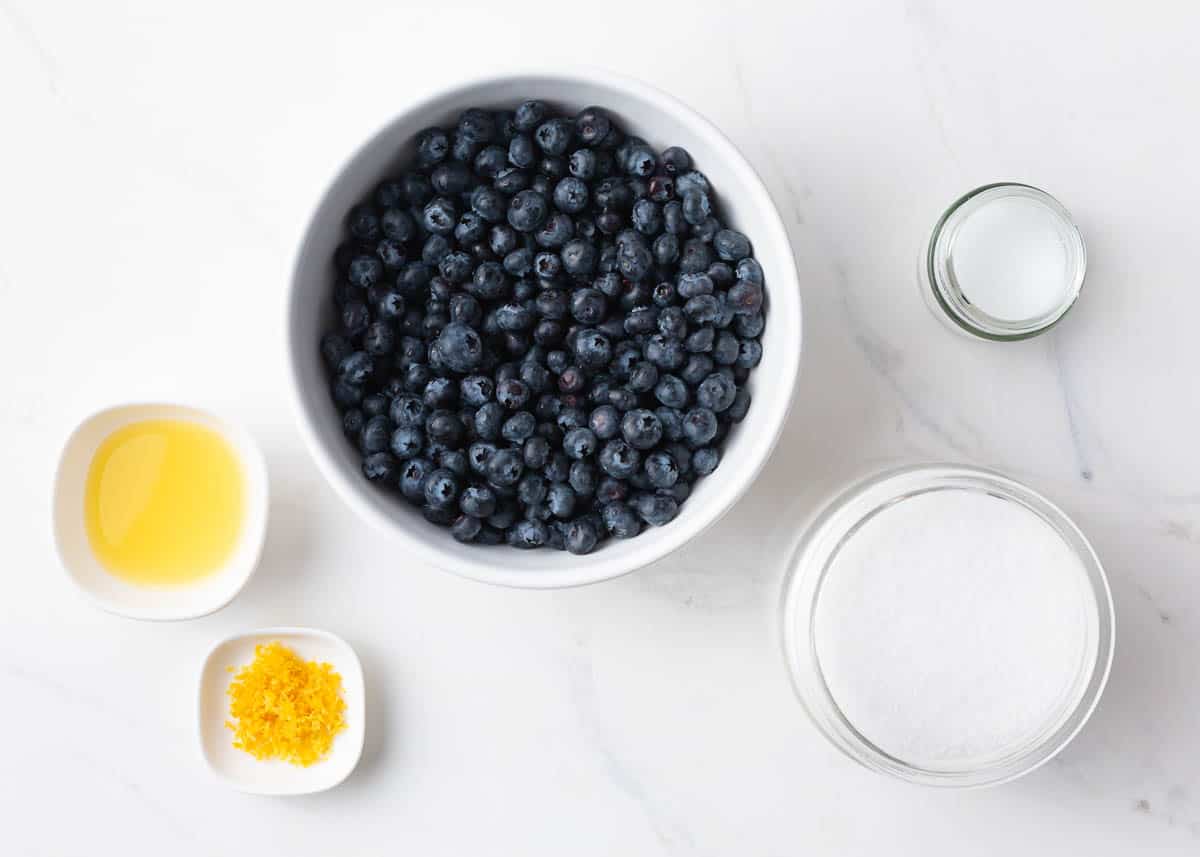 Blueberry jam ingredients on marble counter.