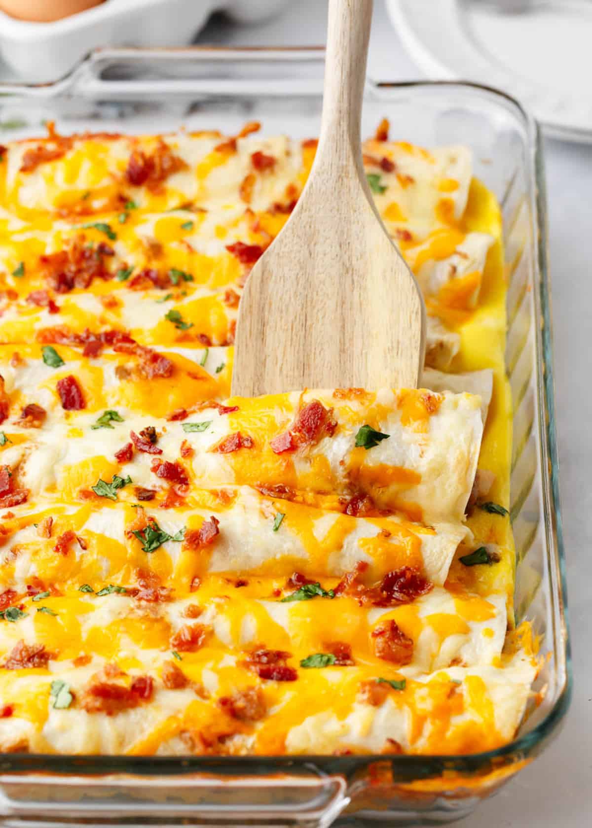 Breakfast enchilada casserole with wooden spoon.