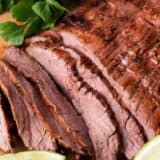 Sliced carne asada on a wooden board.