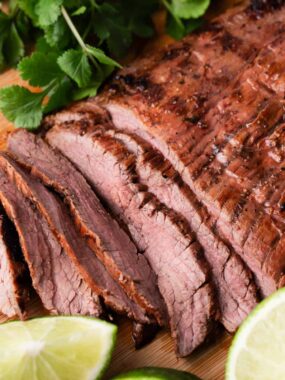 Sliced carne asada on a wooden board.