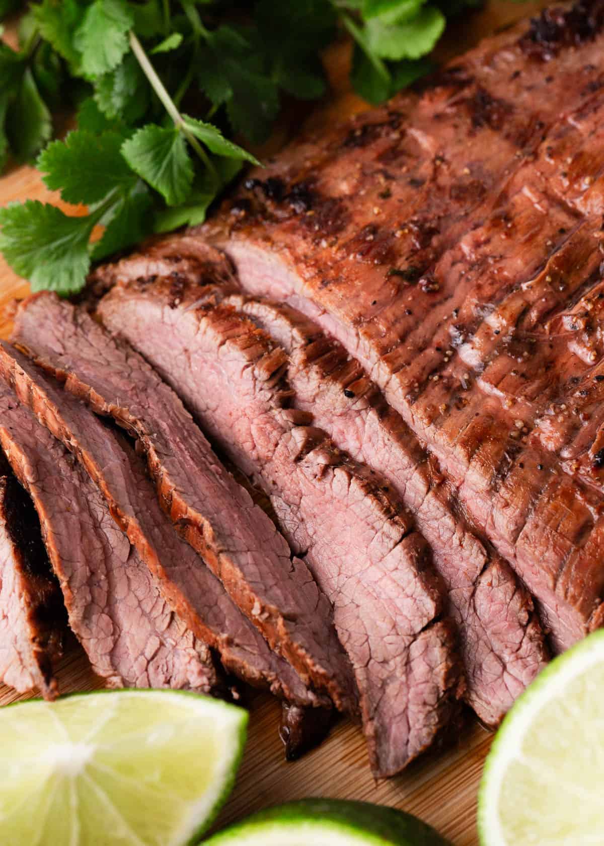 Sliced carne asada on a wooden board.