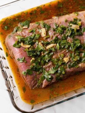 Carne asada marinating in glass dish.