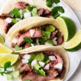 Carne asada tacos on a white plate.