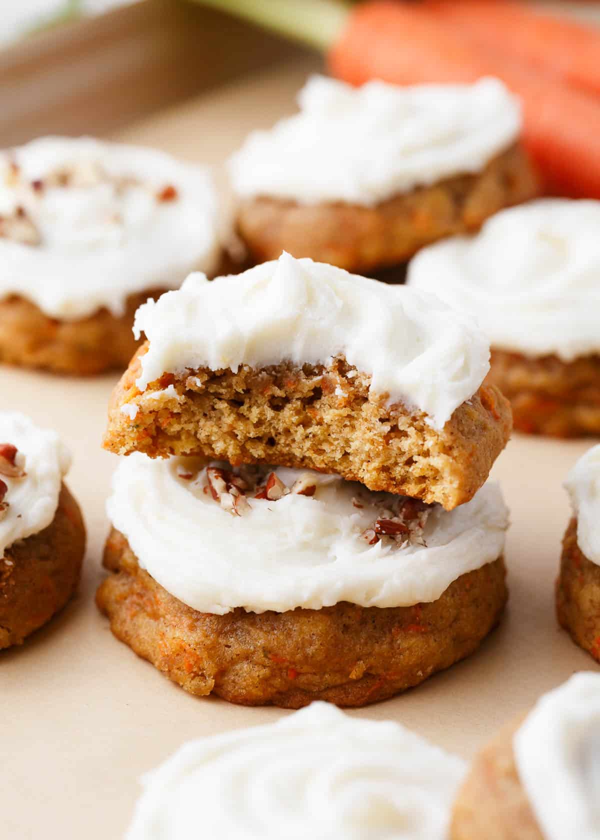 Carrot cake cookies stacked with a bite missing.