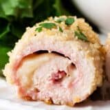 Sliced chicken cordon bleu on white plate.