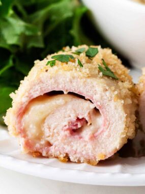 Sliced chicken cordon bleu on white plate.