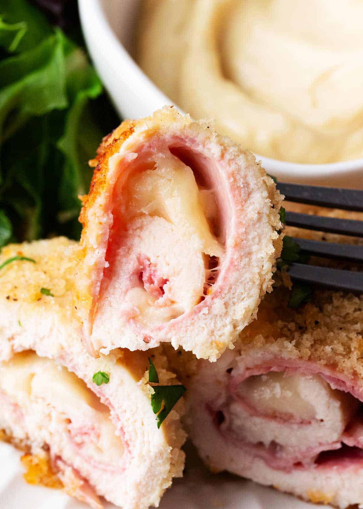 Bite of chicken cordon bleu on a plate.