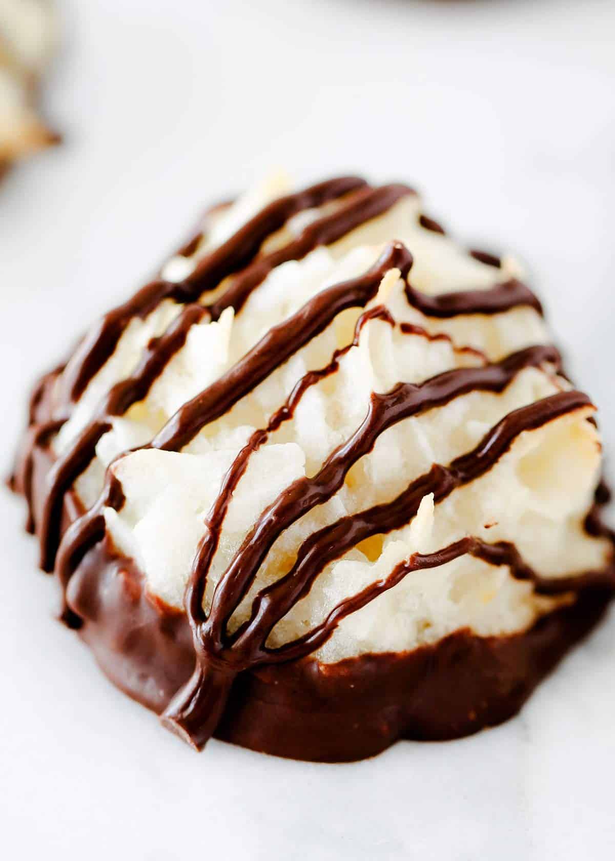 One coconut macaroon up close photo drizzled with chocolate on top. 