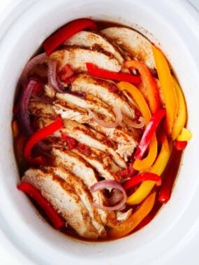 Crockpot chicken fajitas in a white pot.