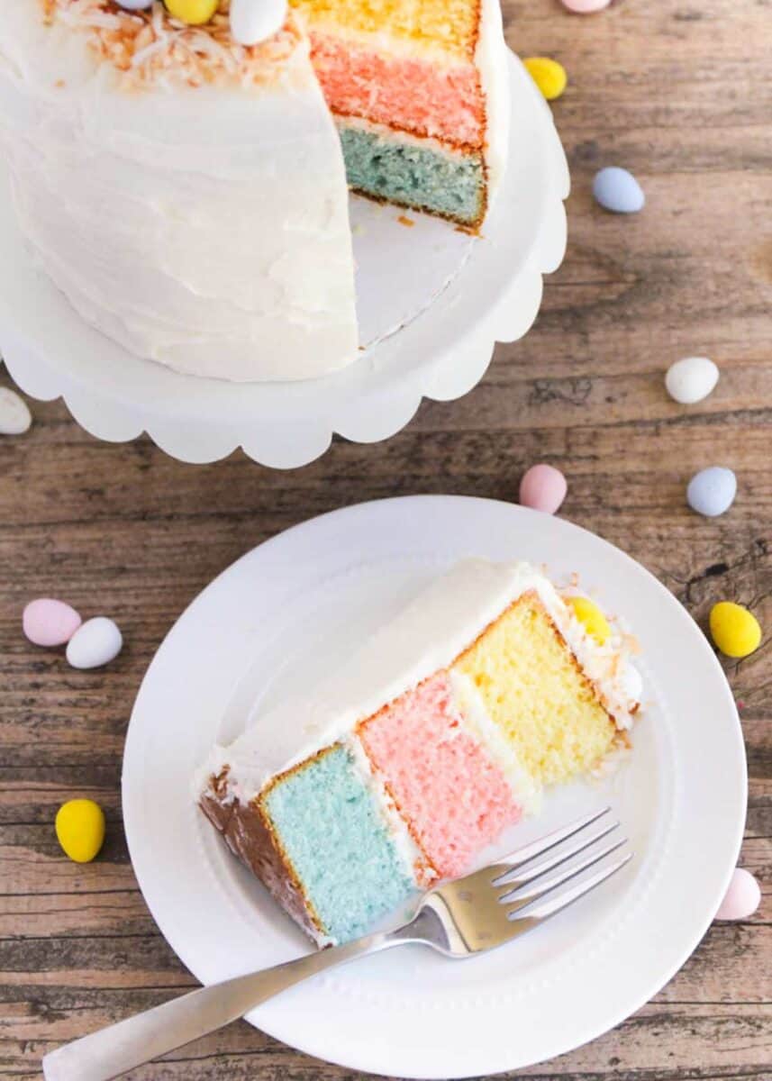 Slice of Easter cake on a white plate with mini cadbury eggs. 