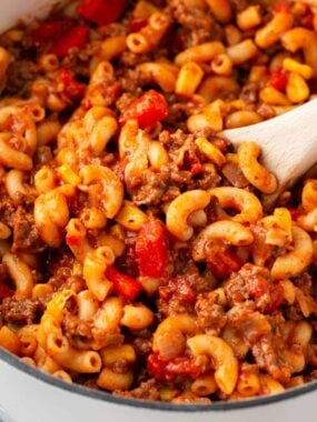 Goulash in a white pot with wooden spoon.
