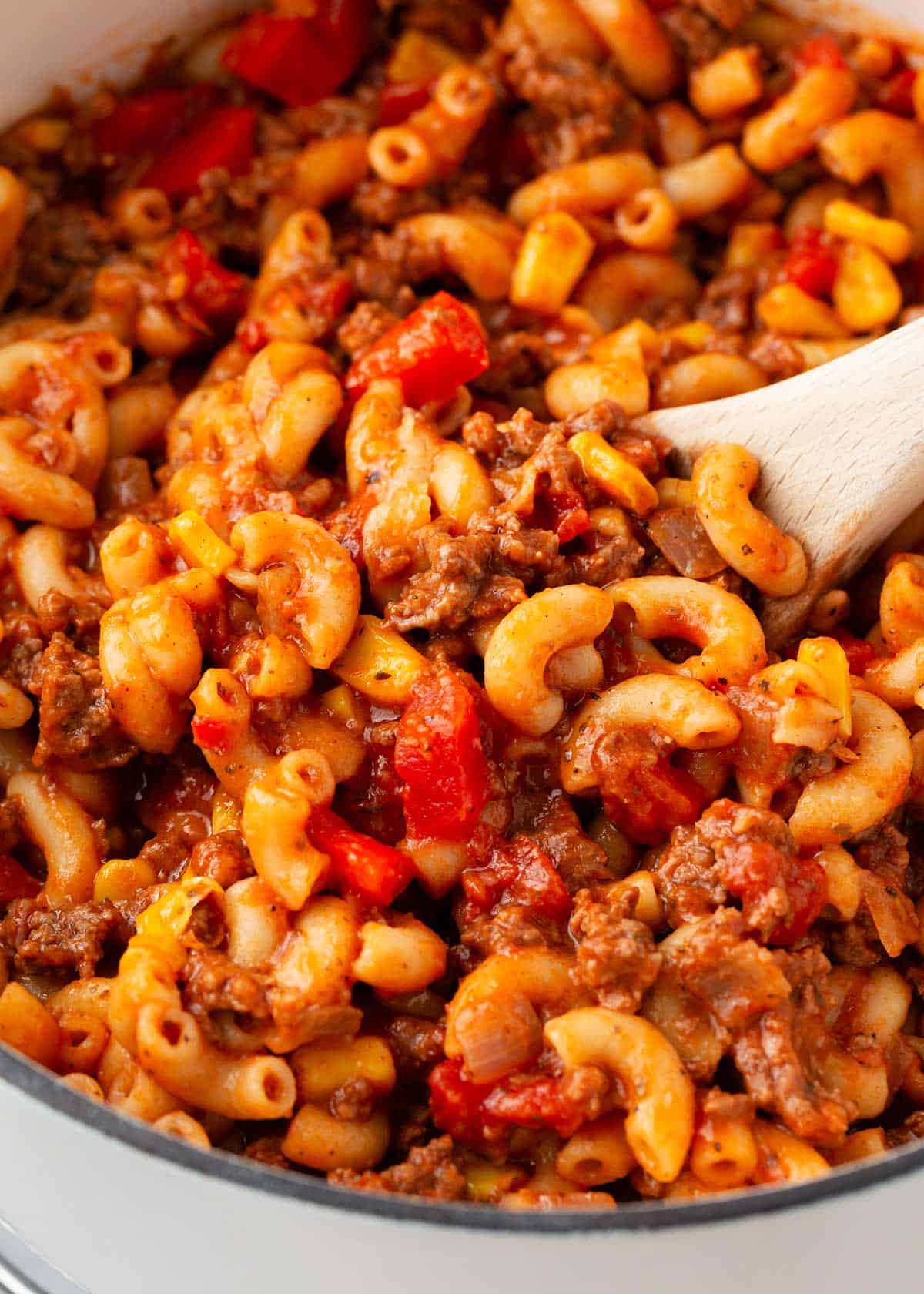 Goulash in a white pot with wooden spoon.