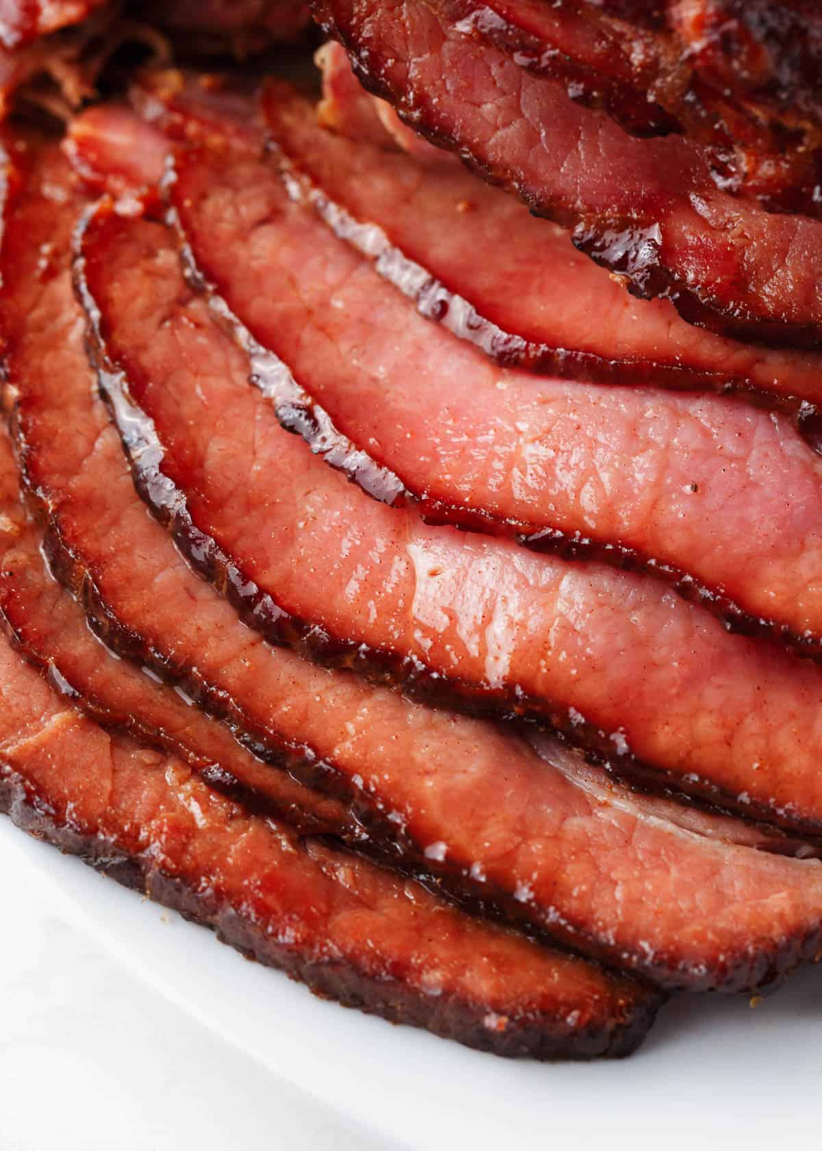 Sliced honey baked ham recipe on white plate.