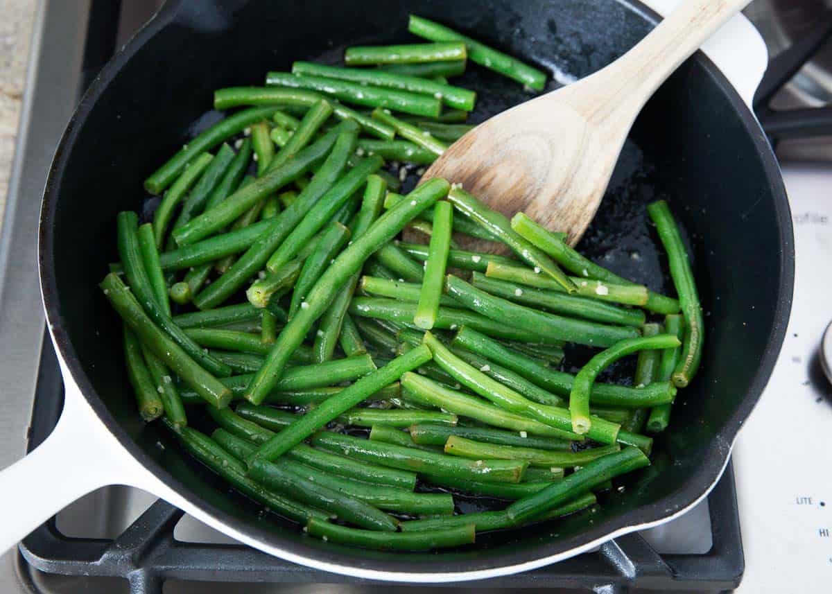 Sautéing green beans in a skillet.