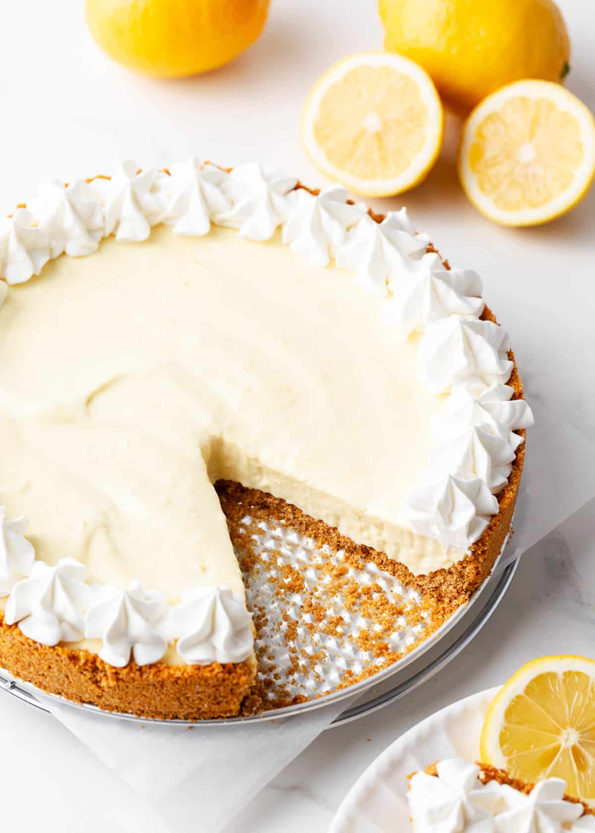 Lemon icebox pie with whipped cream on top and lemons.