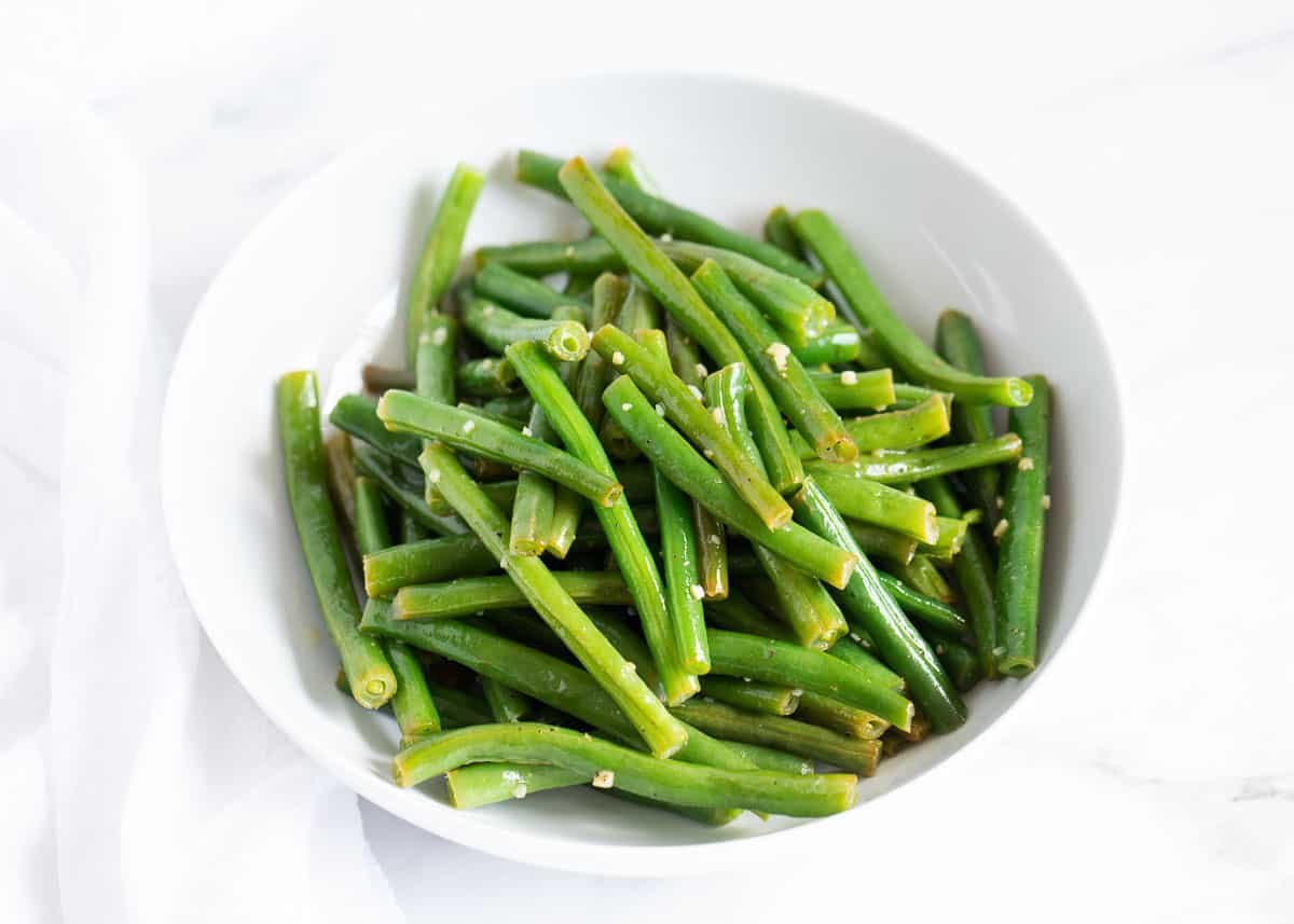 Sautéed green beans in a white bowl.