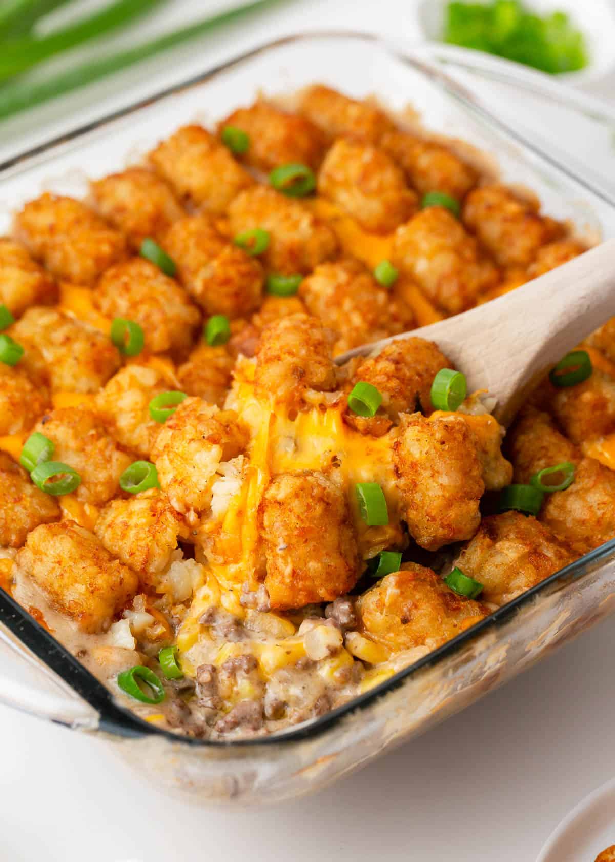 Tater tot casserole in a glass dish with a spoon.