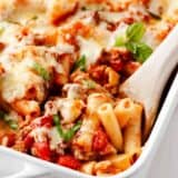 Spoonful of baked ziti in baking dish.