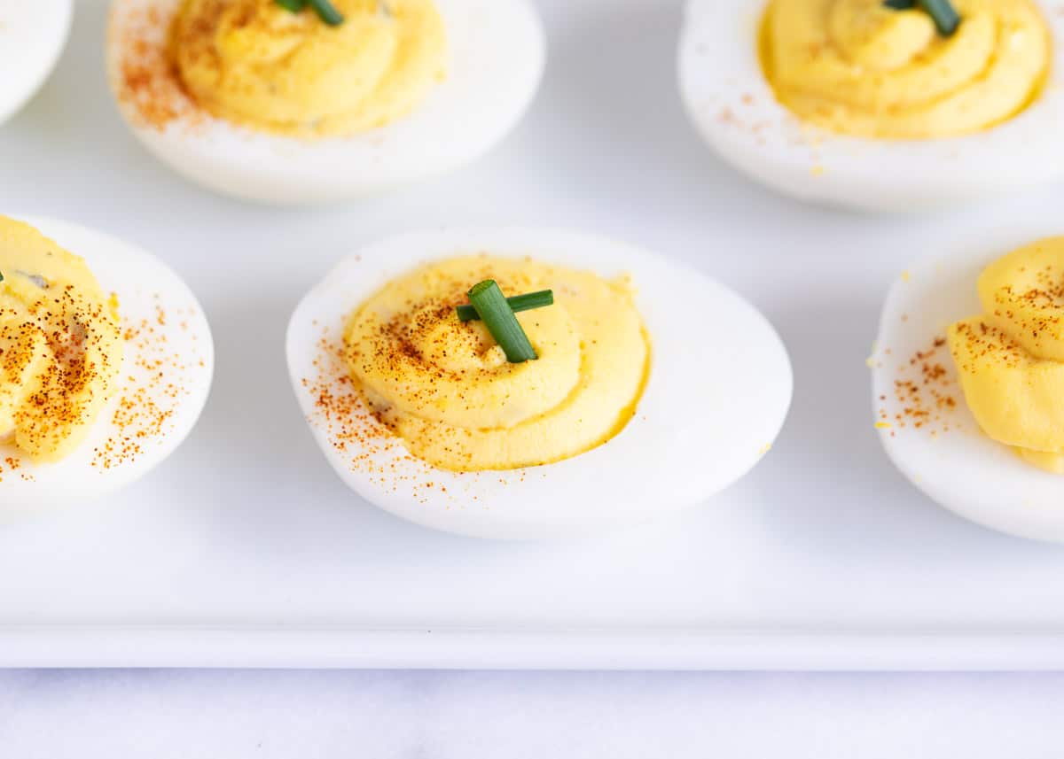 Deviled eggs with paprika on a white plate.