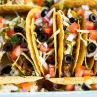 Ground beef tacos stacked in dish.