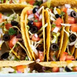 Ground beef tacos stacked in dish.