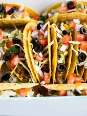 Ground beef tacos stacked in dish.