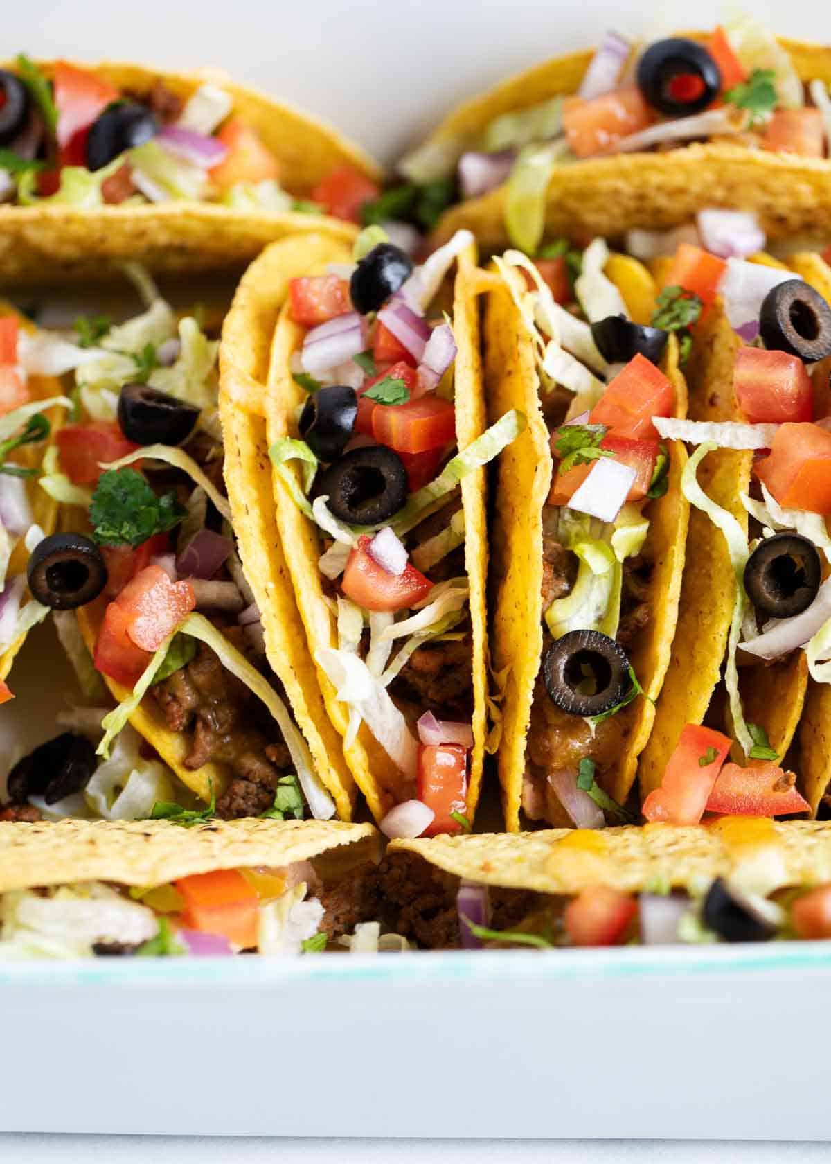 Ground beef tacos stacked in dish.