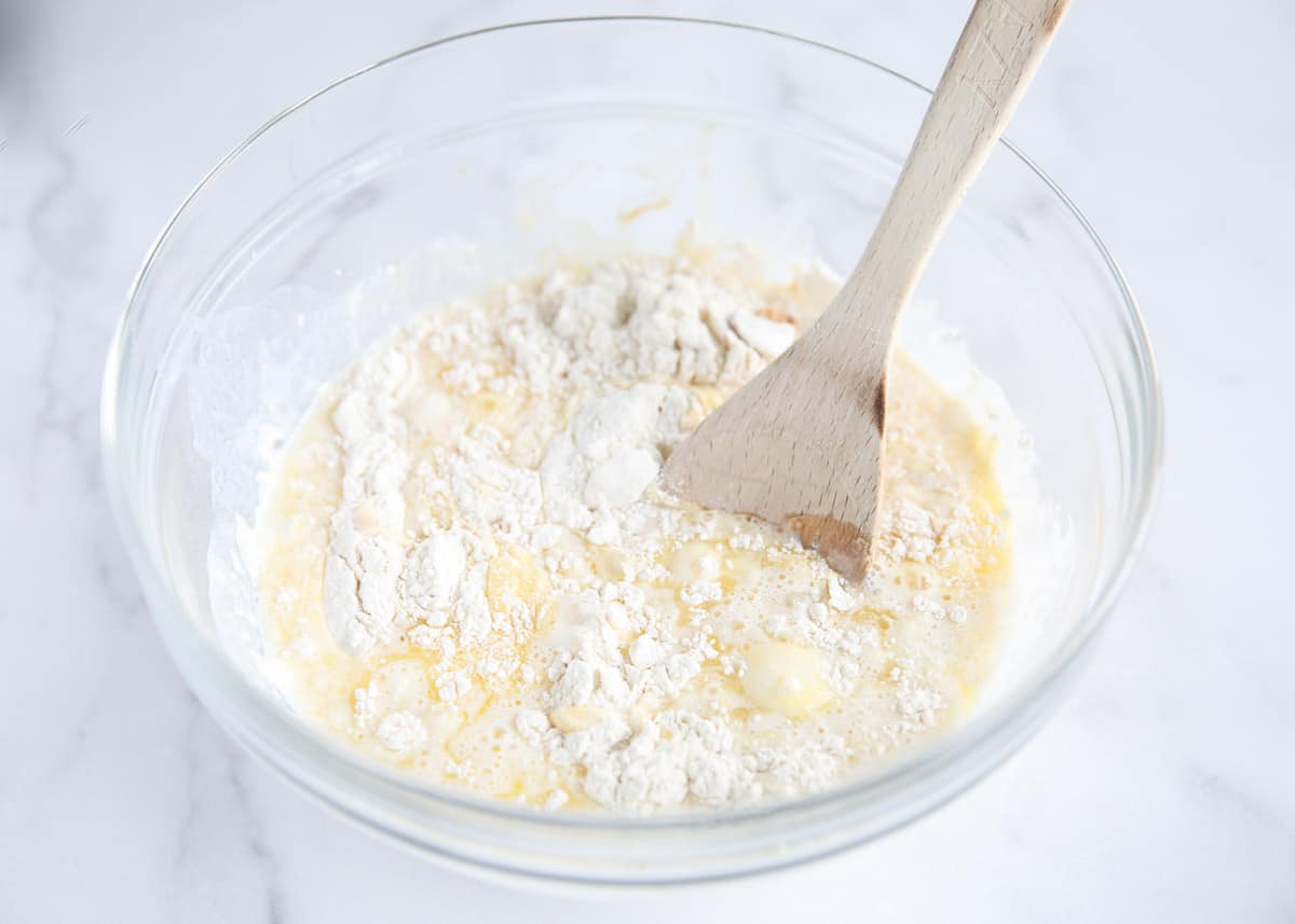 Stirring buttermilk into a flour mixture with butter and baking soda.
