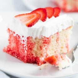A slice of poke cake with sliced strawberries on top.