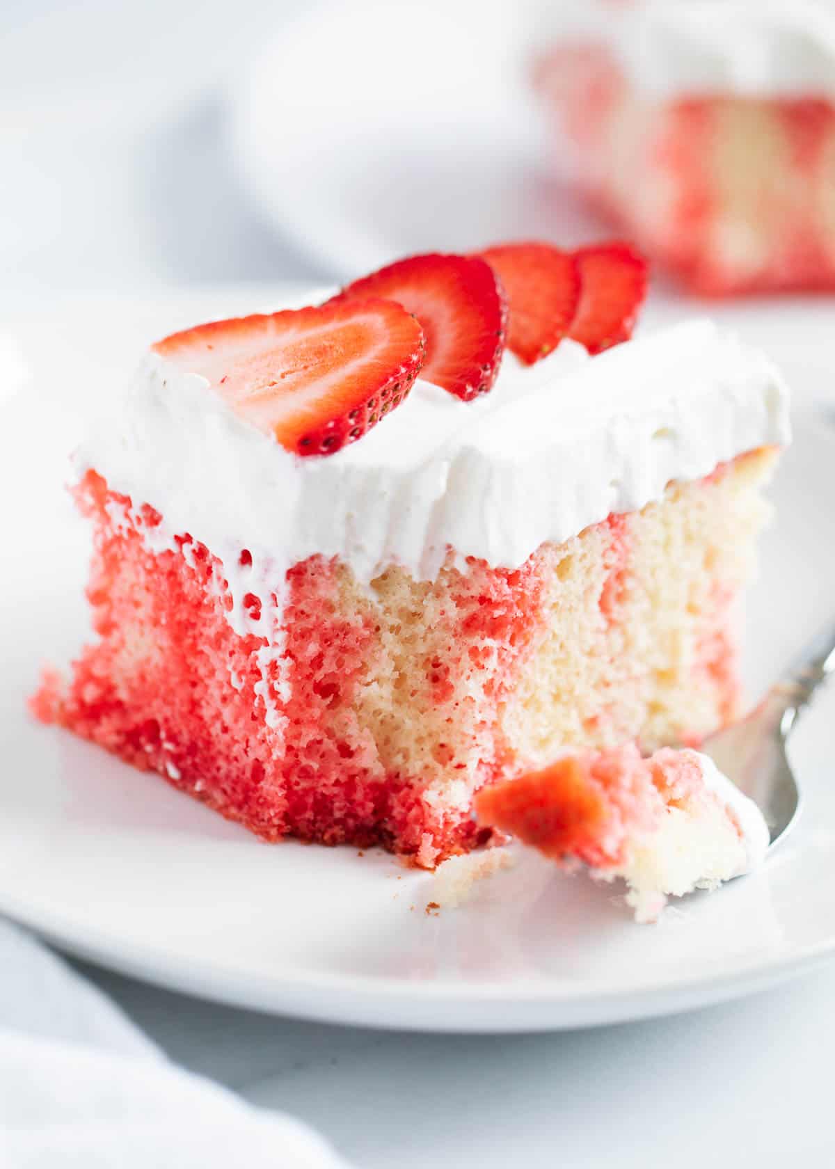 Up close photo of jello poke cake with a bite taken out of it. 