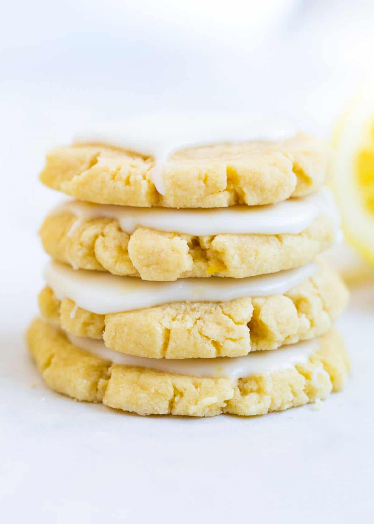 Four glazed lemon cookies stacked on top of each other. 