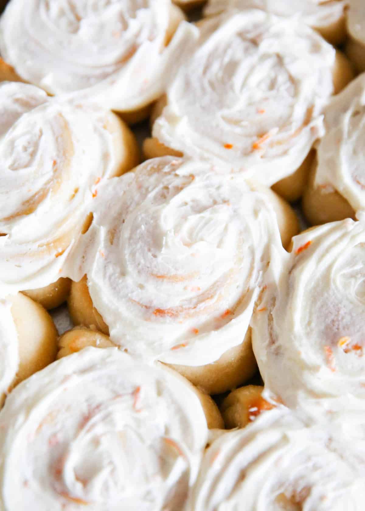 The BEST orange sweet rolls topped with a delicious orange buttercream frosting. Super soft, fluffy and full of fresh orange flavor. This recipe is perfect for breakfast or brunch! Orange rolls in a pan.