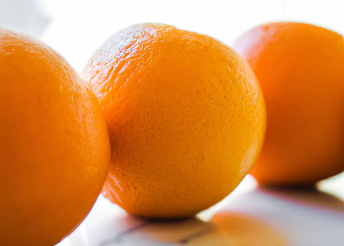 Three oranges sitting on a counter. 