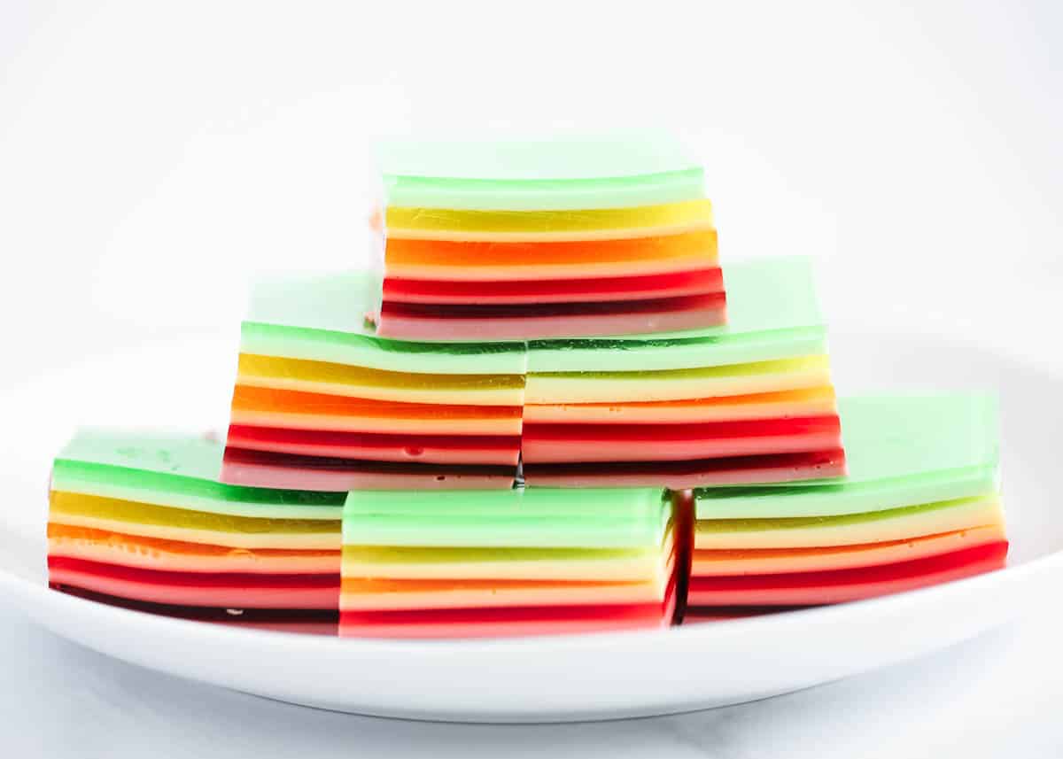 Stack of layered rainbow jello on white plate