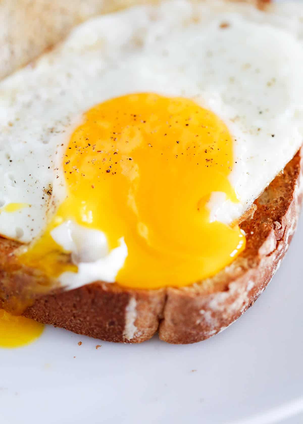 Cut open sunny side up egg on toast.