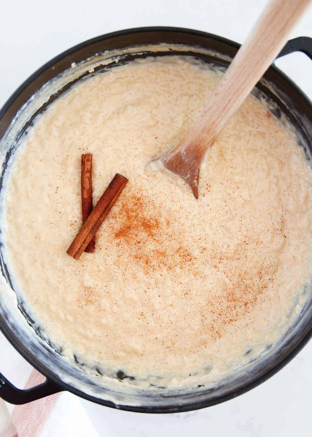 Mexican rice pudding in a black pot with cinnamon sticks.